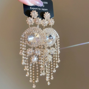 Macro detail of silver tassel earrings with round crystals on black display card
