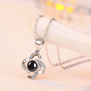 Detail of silver clover pendant necklace with zircon border and central projection stone