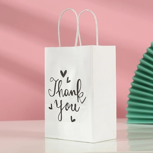 Close-up of white gift bag with Thank You script and heart motifs on a soft background
