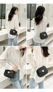 Classic black quilted crossbody bag with golden heart lock shown on a model