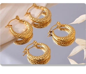 Detail of PVD gold plated C-shape earrings with a unique textured hammered finish