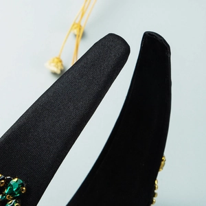 Detail showing high-quality black satin texture and emerald crystal inlays on headband