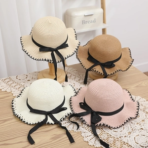 Detail of assorted summer straw sun hats with wavy brims and elegant black bow ribbons