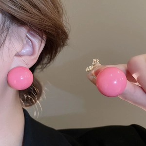Close-up of pink round resin stud earrings showing high glossy finish and worn effect