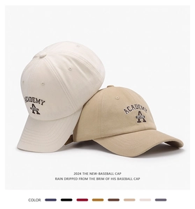 Detail of embroidered academy letters on khaki and beige cotton baseball caps
