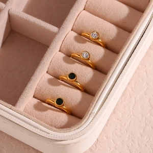 Detail of 18K gold-plated earrings with clear and emerald green zircons in a velvet box