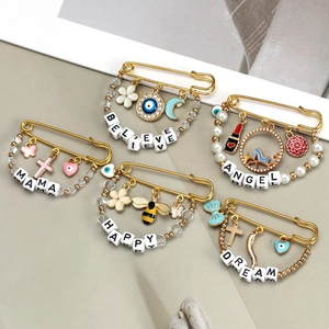 Detailed view of gold safety pins with letter beads and evil eye enamel charms