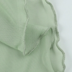 Close-up of mint green sheer mesh fabric with ruffle edge detailing and fine net texture