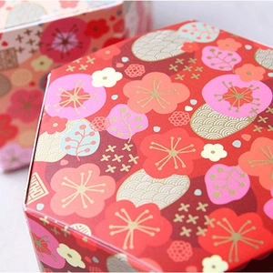 Hexagonal red gift box featuring golden plum blossom patterns and festive texture