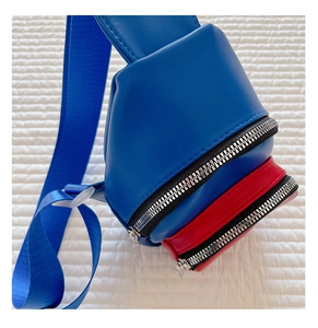 Detail of red and blue kids crossbody bag with double zippers and nylon shoulder strap