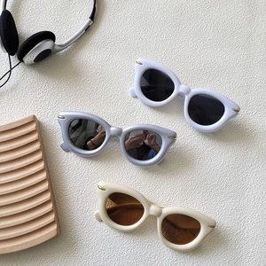 Modern thick-frame cat-eye sunglasses with gold dot accents in white, blue, and cream