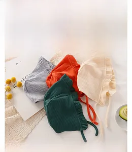 Dettaglio in piano di cappellini in maglia per neonati con balze e lacci laterali