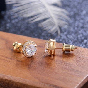 Macro detail of round halo zircon stud earrings in gold finish on a rustic wood stand