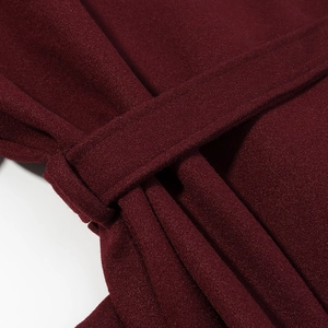 Close-up of wine red wool coat waist belt detailing with refined stitching craftsmanship