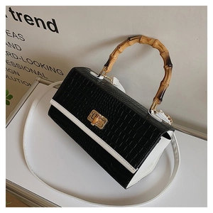 Detail of bamboo handle and gold hardware on black and white crocodile pattern bag