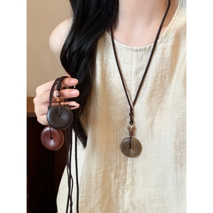 Detalle de collar con colgante de aro de madera vintage y cordón trenzado étnico