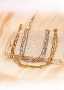 Detail of gold and silver double-layer stainless steel bracelets on stone base