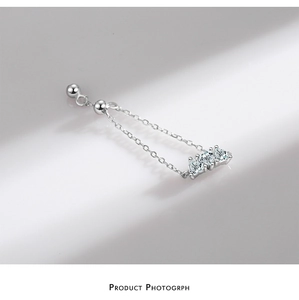 Detail of silver drop earrings with three clear zircons and minimalist chain design