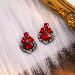 Macro shot of red crystal and rhinestone vintage earrings on white plush fabric