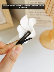 Macro detail of white frangipani flower hair clip with a sturdy black metal duckbill grip