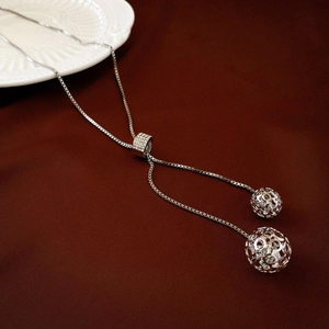 Close-up of silver long Y-necklace with rhinestone slider and hollow sphere pendants