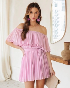 Detail of pink off-shoulder pleated romper with elastic waist and ruffled neckline