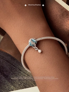 Gros plan du bracelet tressé argenté avec pendentif coquillage bleu et perle