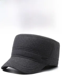 Detail of gray flat top military cap featuring wool texture and metal logo plaque