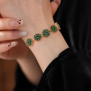 Macro shot of green zircon flower bracelet on wrist with elegant black sleeve background