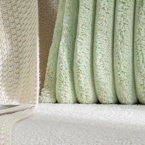 Close-up of soft light green faux rabbit fur pillow with vertical striped plush texture