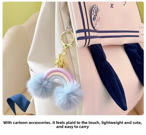 Close-up of bohemian rainbow charm with blue pom-poms hanging on a canvas backpack