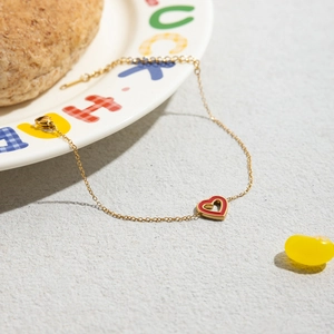 Detail of gold heart bracelet with red enamel pendant and adjustable extension chain