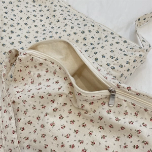 Close-up of silver zipper closure on a floral canvas tote bag with linen texture