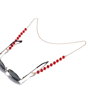 Detail of red faceted crystal beads and gold chain on an eyewear strap accessory