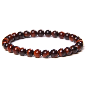 Macro detail of polished red tiger eye stone beads on a stretch bracelet with glossy finish