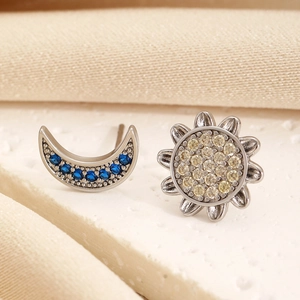 Macro shot of asymmetric sun and moon stud earrings with blue and yellow gemstones