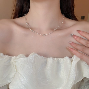 Detail of a French rose pearl layered necklace worn by a model with a white ruffle top