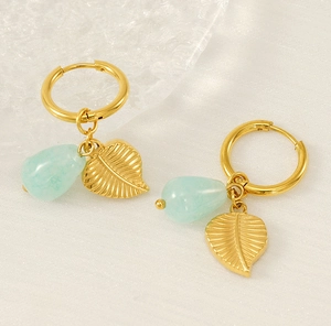 Détail de pendentif feuille en or 18k et pierres vertes sur boucles d'oreilles créoles