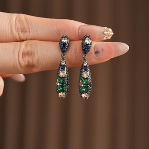 Détail de boucles d'oreilles vintage en forme de goutte avec zircons colorés et métal sombre