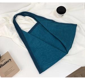 Detail shot of peacock blue tote bag with unique pleated texture and wide strap design
