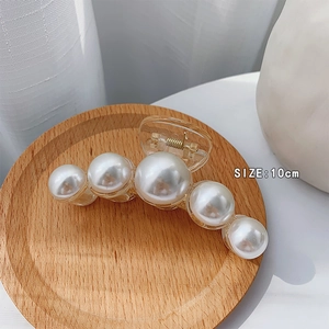 Macro shot of 10cm large pearl hair claw clip with five pearls on a wooden display tray