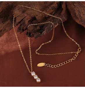 Detailed close-up of triple-set zircon pendant on gold-plated titanium steel chain