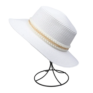 Detail of white straw hat featuring elegant double-layer pearl and gold chain decoration