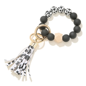 Detail of beaded keychain with matte silicone beads, wooden bead and cow print leather tassel