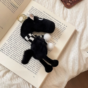 Detail of black flocked pony keychain with a striped scarf on an open vintage book