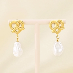 Detailed close-up of golden heart knot earrings with white baroque pearl pendants