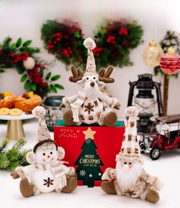 Three knitted Christmas plush ornaments with reindeer, snowman, and gnome on festive decor