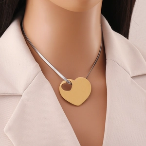 Detailed close-up of a two-tone heart pendant with gold finish on a silver snake chain