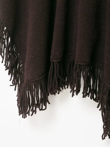 Detailed macro view of dark coffee knit poncho with elegant tassel fringe edge