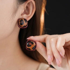 Boucles d'oreilles carrées léopard marron portées et montrées en détail pour la texture
